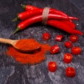 Whole and sliced Ã¢â¬â¹Ã¢â¬â¹red pods of chili pepper, wooden spoon with paprika Royalty Free Stock Photo